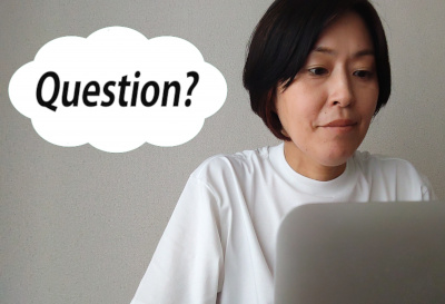白いTシャツの女性がパソコンの間にいるアップの写真です。左側に「question」と書かれた吹き出しがあります。