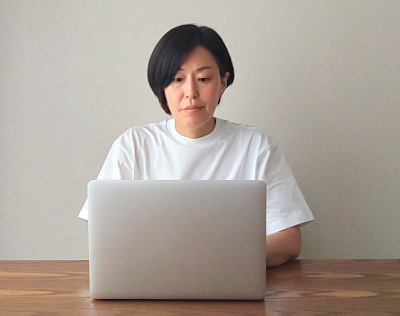 白いTシャツを着て、パソコンに向かう女性の写真